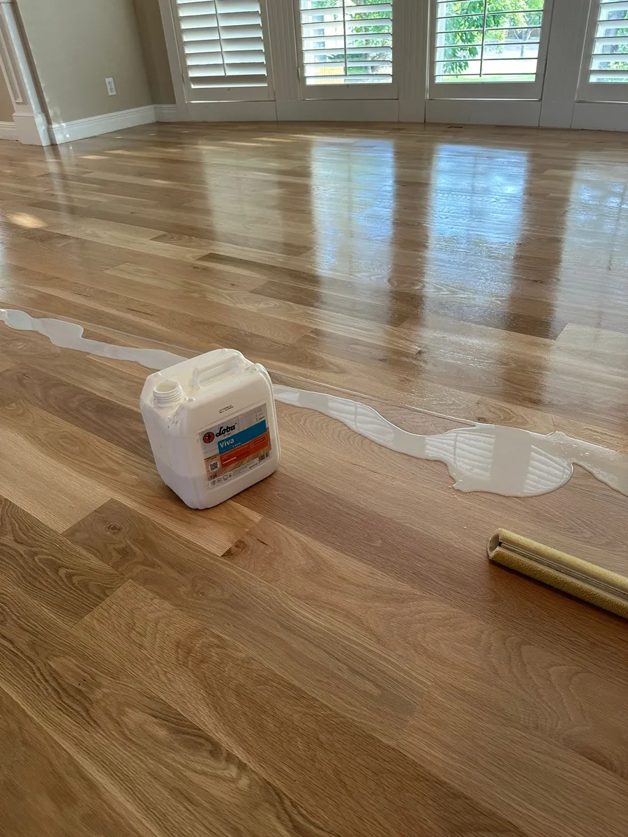 Finish being applied to a freshly sanded oak floor