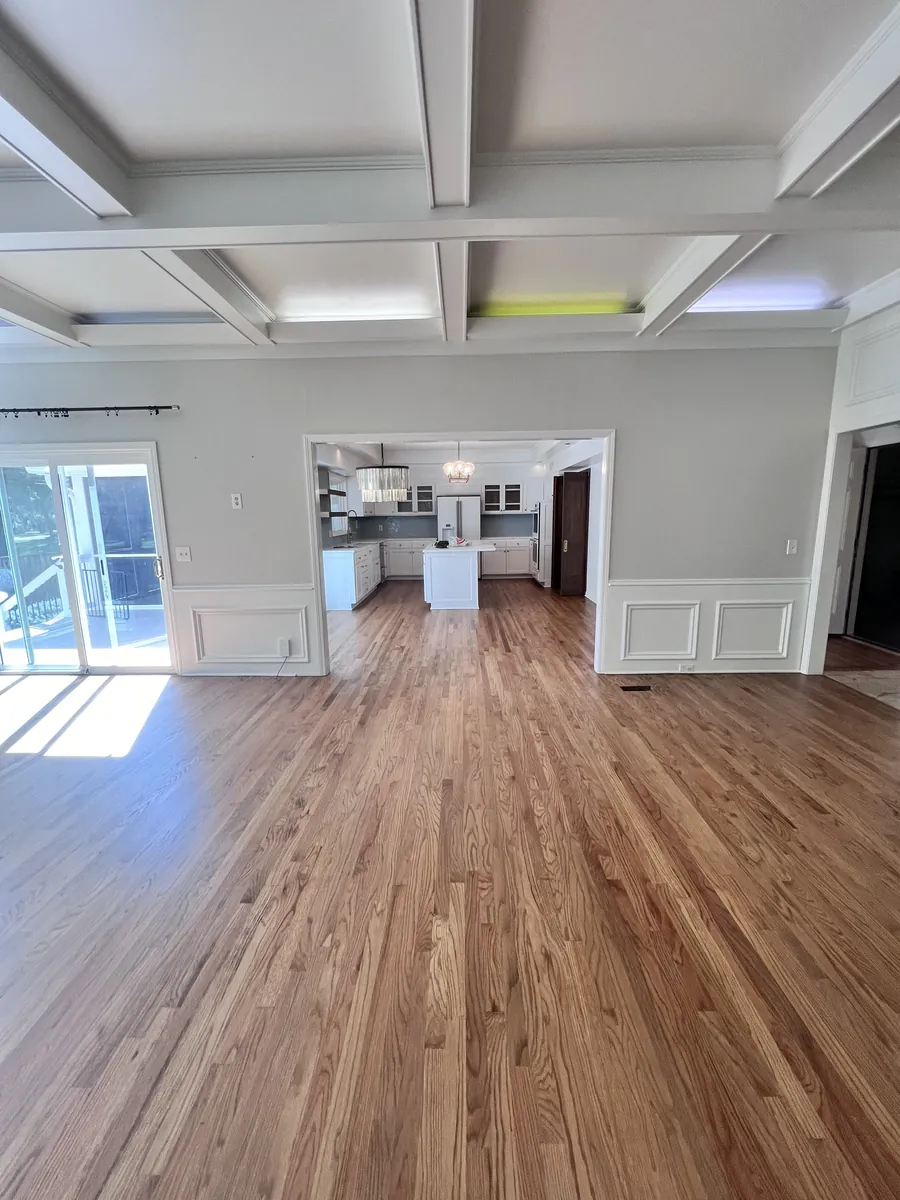 Natural oak floor running from the living room into the kitchen under a coffered ceiling