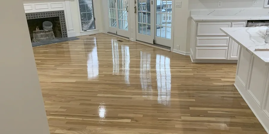 Refinished oak floor with a glossy finish in a kitchen with white cabinets