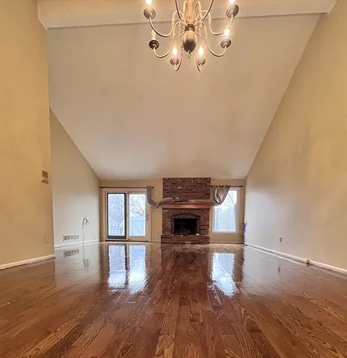 Glossy red oak floor in a vaulted living room with a brick fireplace
