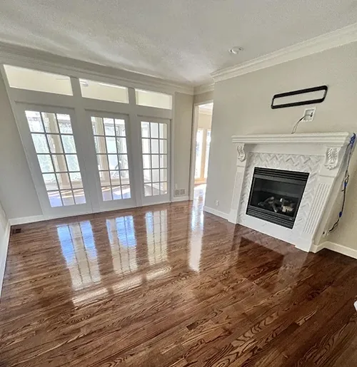 Refinished hardwood in a living room with a white mantel