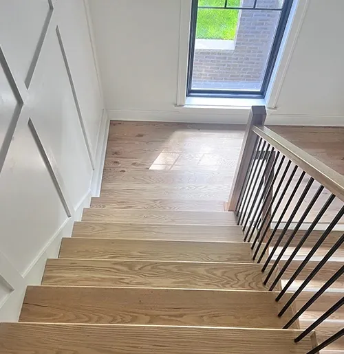 Light oak stairs with black balusters under a skylight