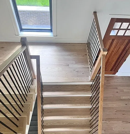 Oak staircase with a stained handrail and black balusters