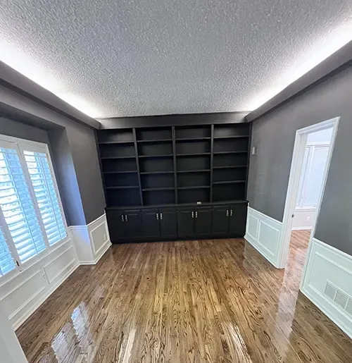 Refinished hardwood in a den with dark built-in bookcases